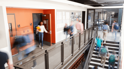a corridor on a college campus, filled with students transitioning between classes