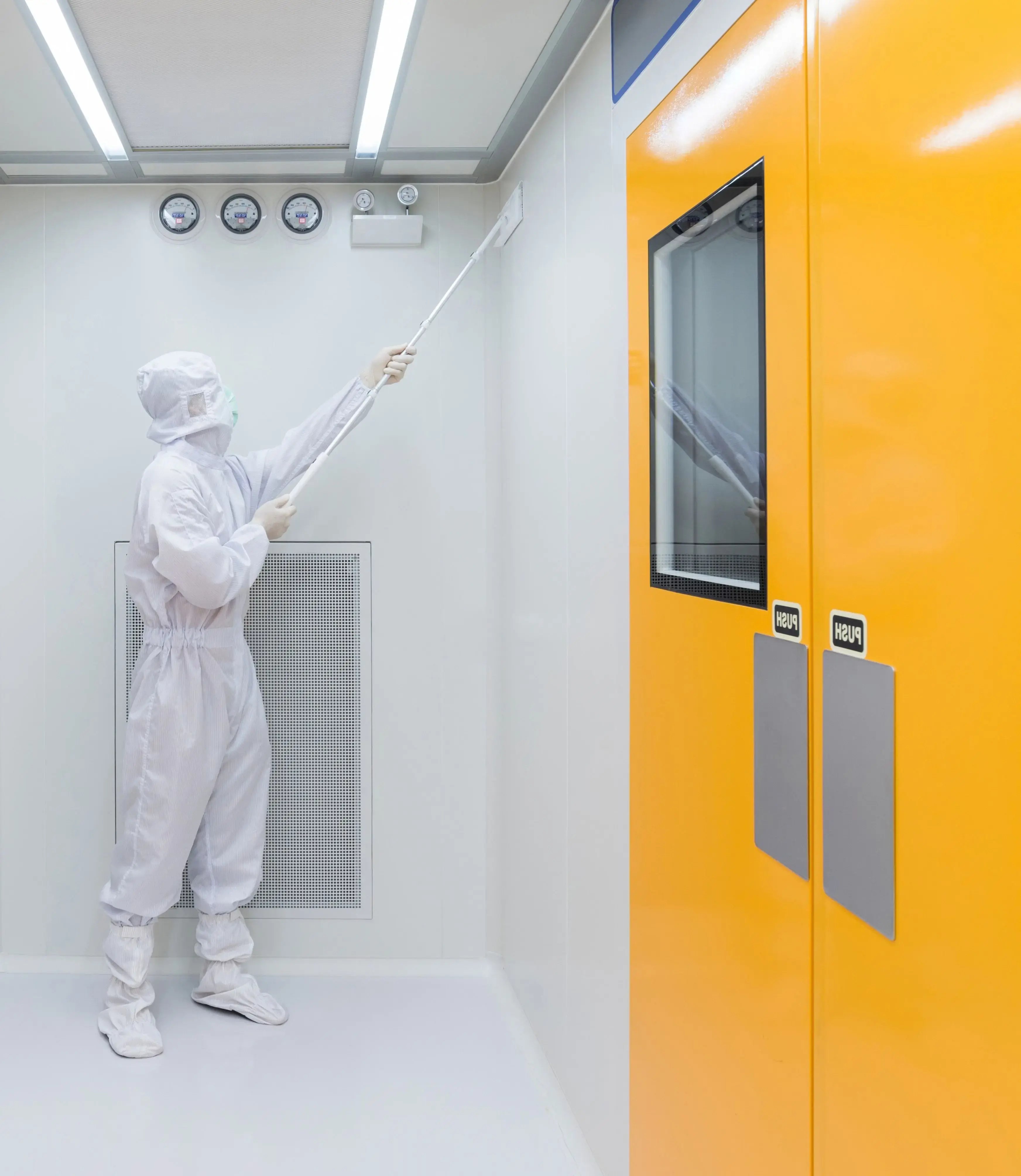 Two cleanroom technicians in protective suits review documentation on a clipboard inside a cleanroom production area.