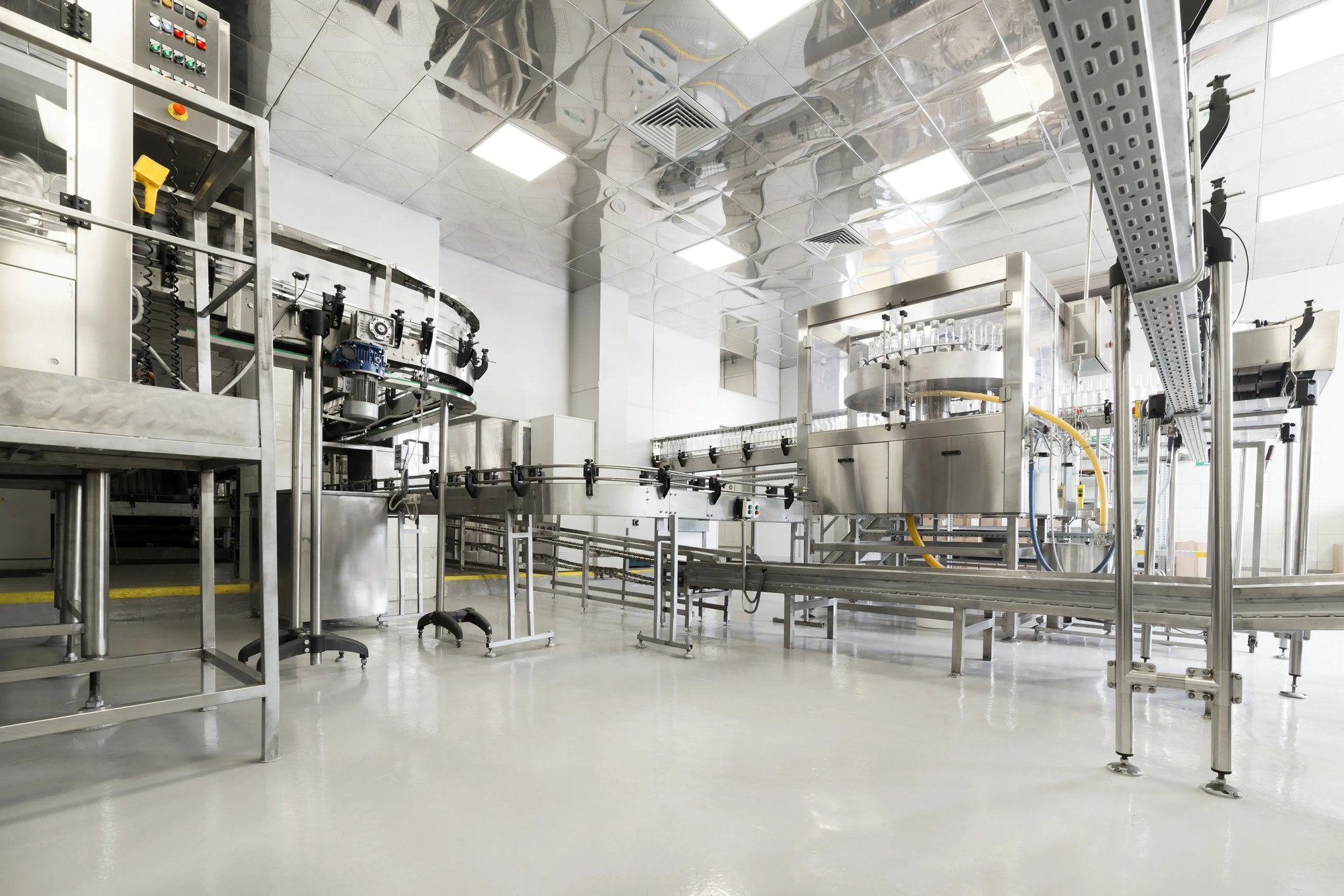 The interior of a clean food and beverage manufacturing facility featuring stainless steel conveyor systems, production equipment, and polished floors.