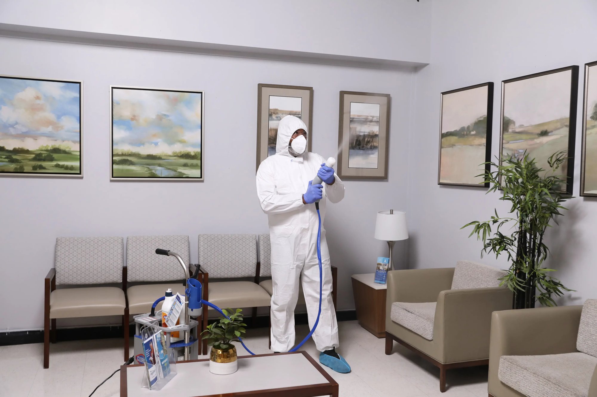 iNX technician using an electrostatic sprayer to disinfect a medical office waiting room.
