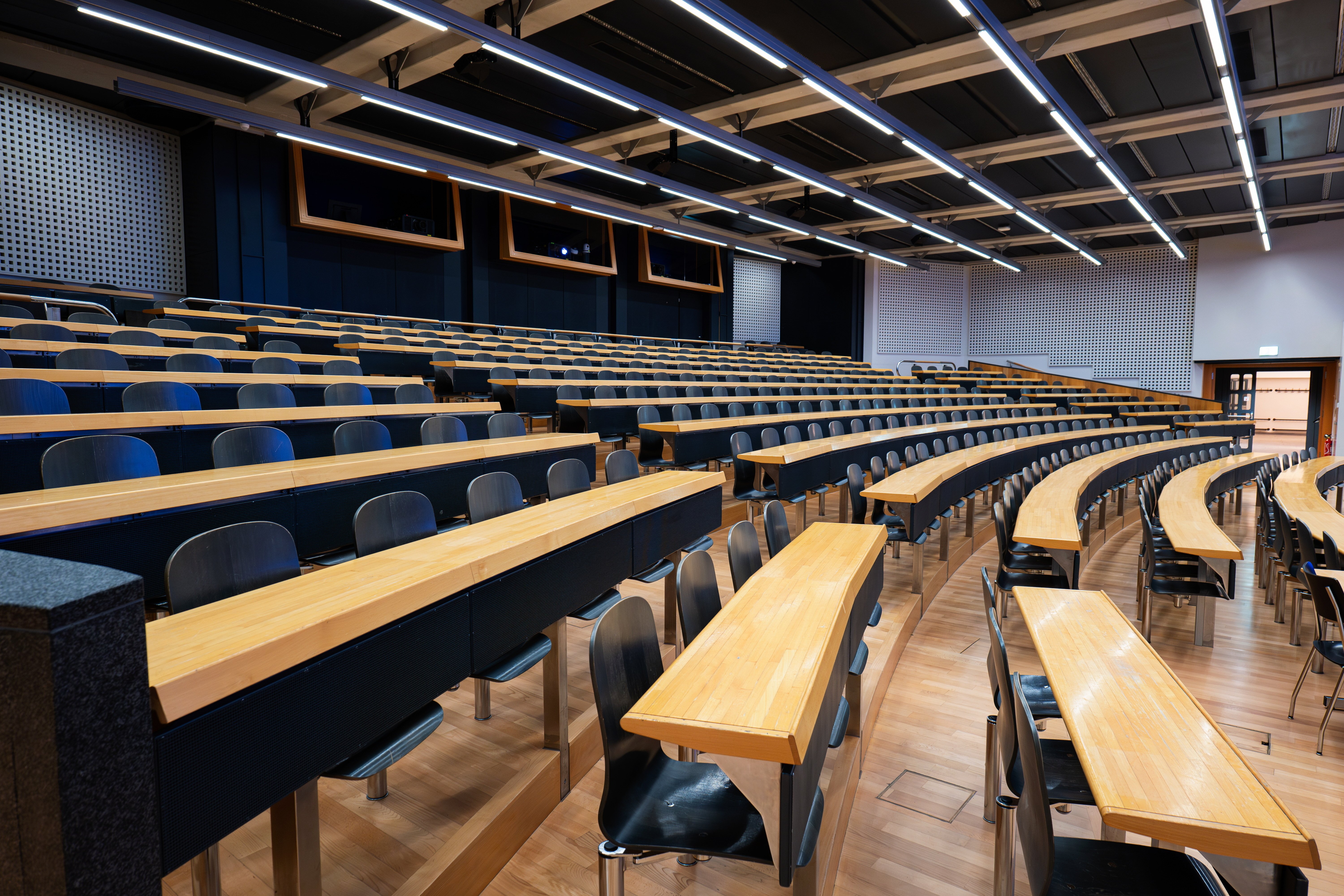 Modern university lecture hall with wooden desks and tiered seating